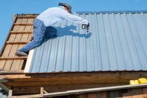 a rural male builder repairs the roof of a house